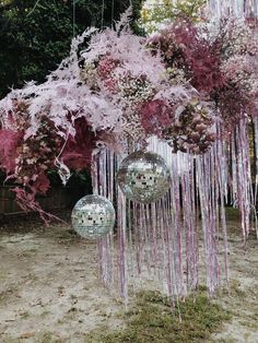 two disco balls hanging from a tree filled with pink flowers