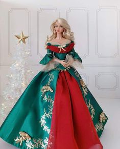 a barbie doll dressed in a green and red christmas dress next to a white christmas tree