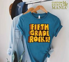 "5th Grade Rocks T-shirt, 5th Grade Teacher Shirt, Fifth Grade Shirt, Back To School Gift, Gift for Teacher, First Day of School Shirt, Fifth Grade Gift, Teacher Tee, 5th Grade TShirt, Back To School Shirt, Teacher Appreciation, 5th Grade Team Shirt, Hello Fifth Grade ----- How To Order ----- 1-) Please, check and review all the photos. 2-) Choose your t-shirt size and color. *Different styles of shirts may have different shades of same color choice due to different manufacturer brands. *For this reason, we recommend you to match shirts from the same styles if you want precisely matching colors (ex. Unisex, V-necks, Toddler, etc.). 3-) Click add to cart. You can go back to add more shirts. 4-)Click \"Proceed to check out\". 5-)When you check out, you can add a note to seller for any reques School Tshirt Design Ideas, 5th Grade Shirts, 5th Grade Shirt, 5th Grade Teacher Shirts, 7th Grade Teacher Shirts, 5th Grade Tshirt Ideas, 5th Grade Team Shirts, Fifth Grade Teacher Shirts, School Spirit Shirts Designs