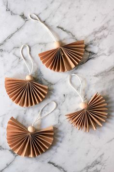 three brown paper fan ornaments on a marble surface