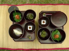 there are many bowls and plates on the mat with chopsticks next to them