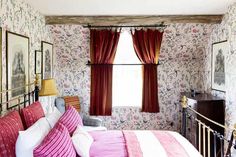 a bed room with a neatly made bed next to a window and pictures on the wall