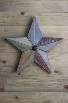 a multicolored wooden star hanging on the wall next to a wood plank floor