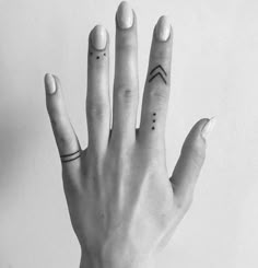 a person's hand with two small tattoos on their fingers