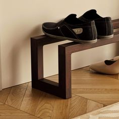 a pair of shoes sitting on top of a wooden bench next to a shoe rack