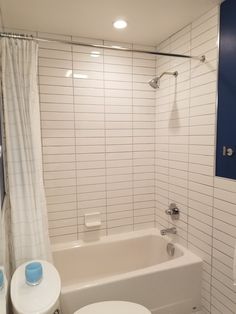 a white toilet sitting next to a bath tub in a bathroom under a sign on the wall