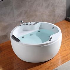 a large white bath tub sitting on top of a wooden floor next to a wall