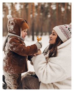 a woman holding a small child in the snow while they both look at each other