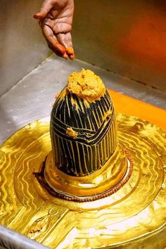 a person reaching for food on top of a gold plate in a metal container with other items around it