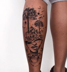 a woman's leg with a tattoo on it and trees in the sky behind her