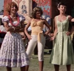 three women in dresses standing next to each other