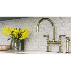 a vase with yellow flowers sitting next to a faucet on a kitchen counter