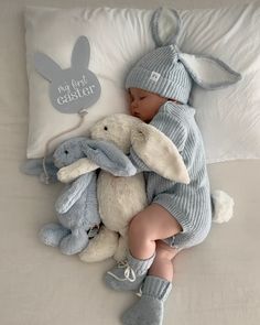 a baby sleeping next to two stuffed animals