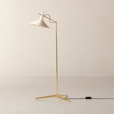 a floor lamp with a white shade on the top and a black cord attached to it