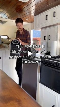 a man standing in the kitchen holding an air conditioner