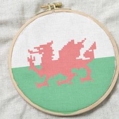 a cross stitch pattern with a pink and green dragon in the center on a white background