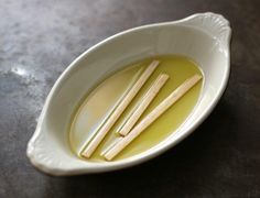 three wooden sticks in a white bowl filled with oil