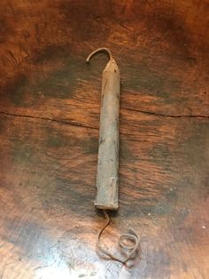 an old metal object sitting on top of a wooden table next to a cord and a piece of wood