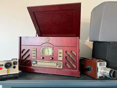 an old fashioned radio sitting on top of a table next to two cameras and a speaker