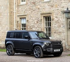 a black land rover parked in front of a stone building