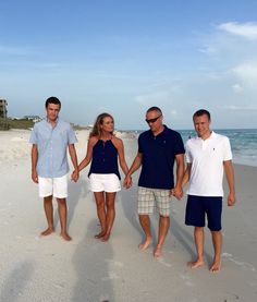 four people standing on the beach holding hands