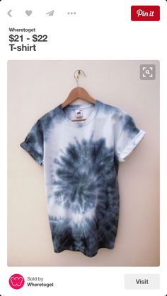 a blue and white tie - dye shirt hanging on a hanger next to a wall