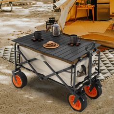 a cart with food on it sitting in the middle of a camping area next to a tent