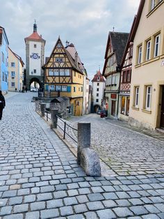 a cobblestone street with buildings and a person on a bike in the distance