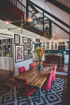 a dining room table with red chairs and pictures on the wall