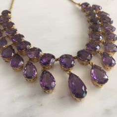 Details: Stunning Amethyst and 14K gold necklace. The necklace along has 34 amethyst ranging in size from 8mm x 9mm to 9.8mm x 17.6mm. The drop on the largest amethyst measures 34.6mm (about 1.4 inches). The appraisal value of this is $5,500. From Appraisal: One (1) fourteen karat yellow gold amethyst fringe necklace. Set in four prong open work gallery crowns are seventeen (17) faceted oval amethysts, graduating out from the center (12.85 x 9.74 x 5.54 mm), weighing approximately 53.77 carats c Opulent Round Necklaces For Formal Occasions, Elegant Purple Jewelry For Formal Occasions, Elegant Yellow Gold Amethyst Jewelry, Elegant Purple Evening Jewelry, Elegant Purple Jewelry For Evening, Opulent Formal Necklaces With 17 Jewels, Elegant Gold Amethyst Jewelry, Elegant Amethyst Jewelry, Elegant Yellow Gold Amethyst Necklace