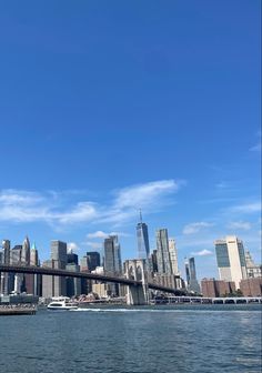 the skyline of new york city is seen from across the water in front of a bridge