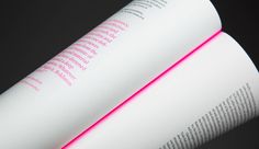 an open book with pink light coming out of the top and bottom pages, on a black background