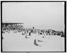 many people are on the beach with umbrellas