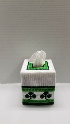 a tissue box that is decorated with shamrocks and clovers on the front, sitting on a white surface