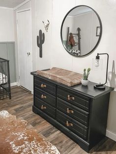 a black dresser sitting in front of a mirror on top of a hard wood floor