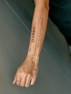 a person's arm with an arrow and phases tattoo on the left side of their arm