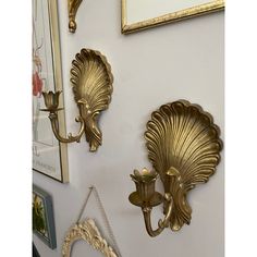 three gold sconces are hanging on the wall next to pictures and other decorative items