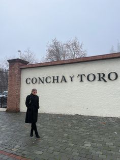 a woman standing in front of a sign that says concha y'toro