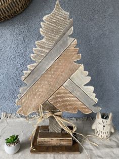 a wooden christmas tree sitting on top of a table next to a potted plant