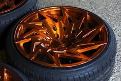 three shiny orange rims and tires on the ground