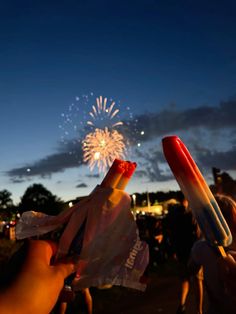 two people are holding up their cell phones with fireworks in the sky behind them at night