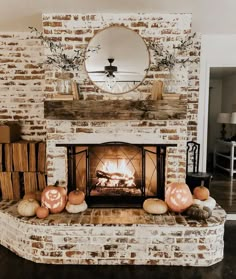 a brick fireplace with pumpkins on the mantle