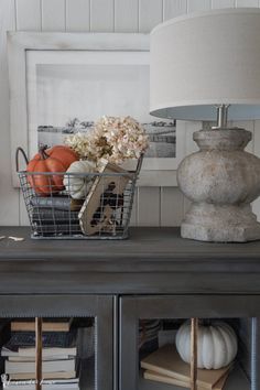 a basket filled with flowers sitting on top of a wooden table next to a lamp