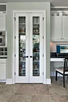 a kitchen with two glass doors and a computer on the counter in front of it