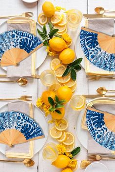 the table is set with yellow and blue plates, silverware, and lemons