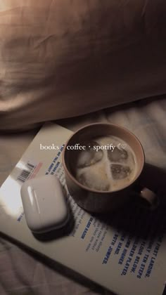 a cup of coffee and a mouse on top of a book next to a pillow