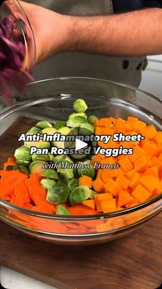 a bowl filled with carrots and brussel sprouts on top of a wooden cutting board