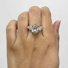 a woman's hand holding an engagement ring with three stones on the middle and one stone in the middle