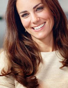 a woman with long brown hair smiling at the camera