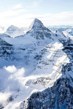 the mountains are covered in snow and clouds as seen from an air plane over them